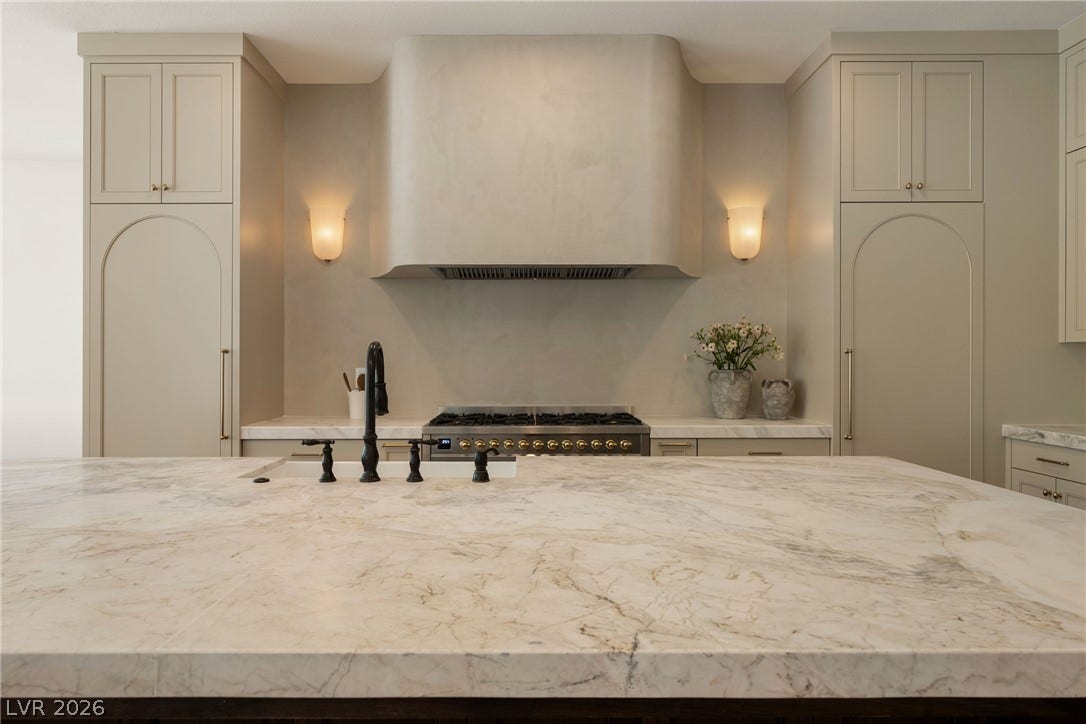 12007 Oakland Hills Drive, Las Vegas, NV 89141 Fine stone countertops elevate this kitchen, anchored by a custom range hood over the gas cooktop.