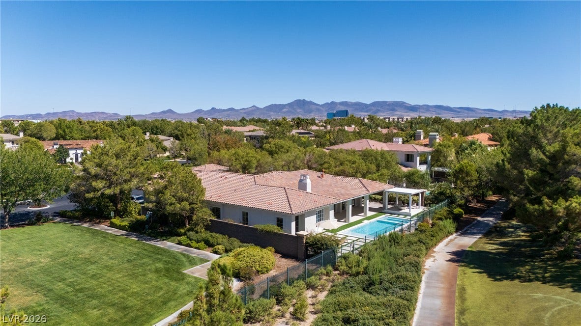 12007 Oakland Hills Drive, Las Vegas, NV 89141 An aerial perspective showcases a tile-roof residence nestled against a mountain backdrop.