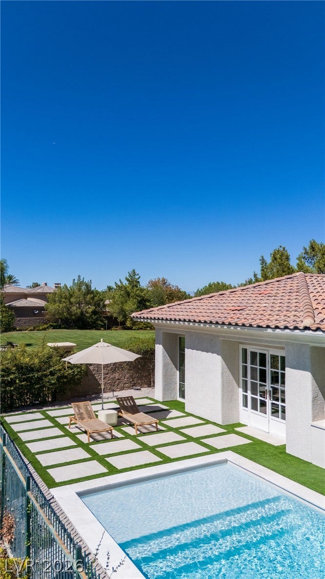 12007 Oakland Hills Drive, Las Vegas, NV 89141 Geometric pavers and synthetic turf border a sparkling pool beneath Spanish tile roofing.