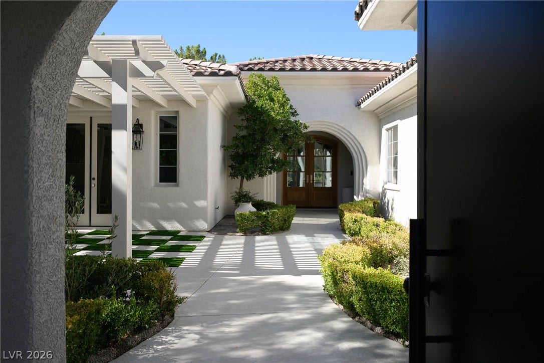 12007 Oakland Hills Drive, Las Vegas, NV 89141 A welcoming concrete pathway leads through a sunny courtyard to the arched double front doors.