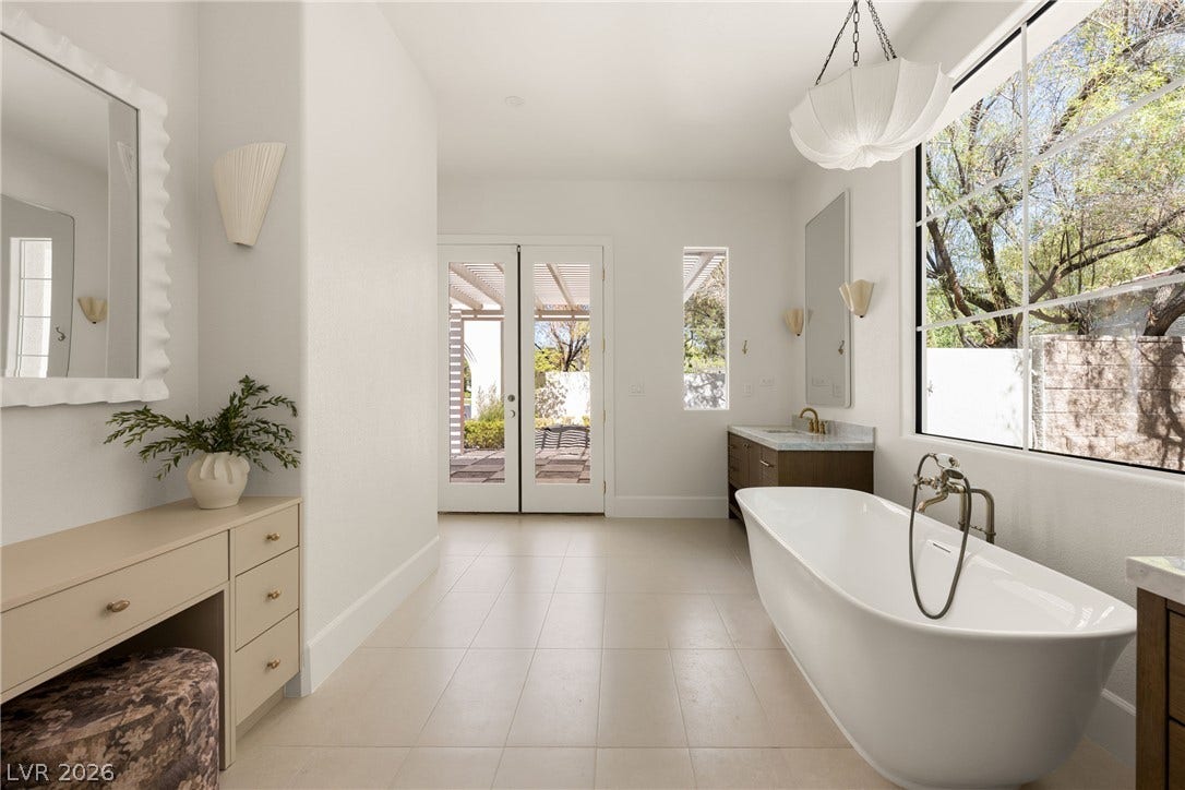 12007 Oakland Hills Drive, Las Vegas, NV 89141 Plentiful natural light fills a spacious bathroom featuring a freestanding tub and tiled floors.
