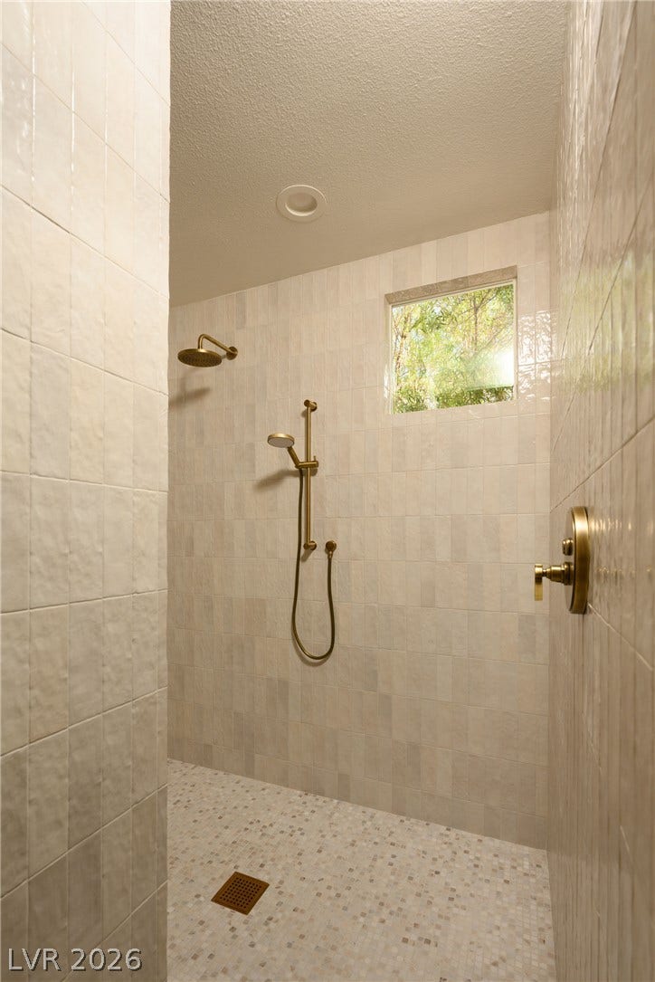 12007 Oakland Hills Drive, Las Vegas, NV 89141 Gleaming wall tiles and elegant brass fixtures define this walk-in shower oasis.