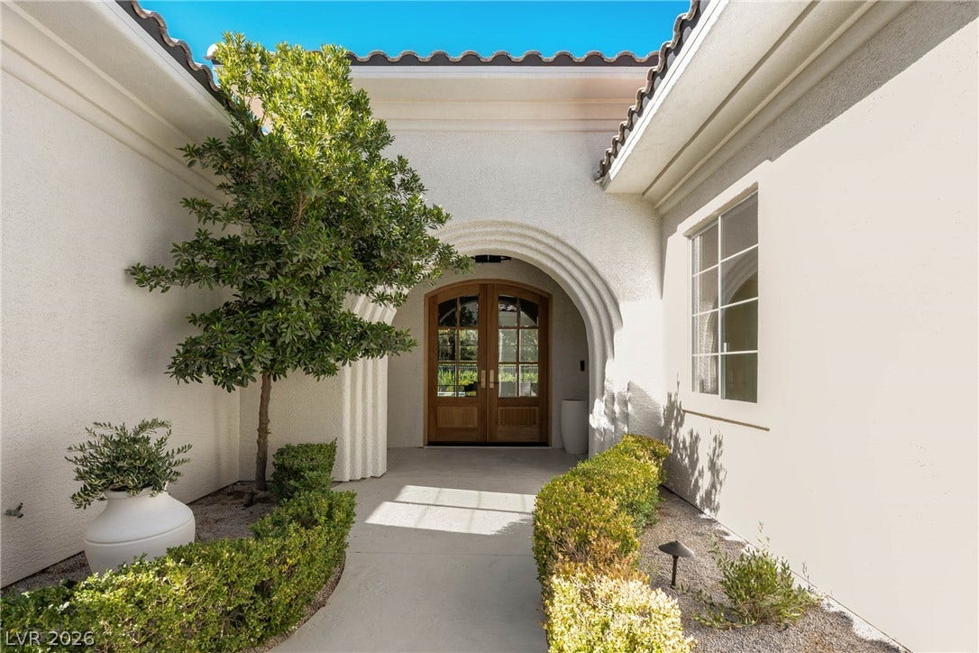 12007 Oakland Hills Drive, Las Vegas, NV 89141 An arched entry porch leads to elegant double glass doors framed by stucco walls.