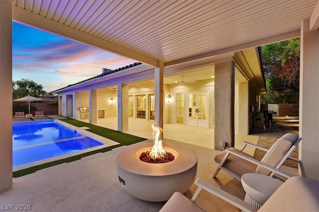 12007 Oakland Hills Drive, Las Vegas, NV 89141 An inviting covered patio features a glowing fire pit beside a sparkling swimming pool.