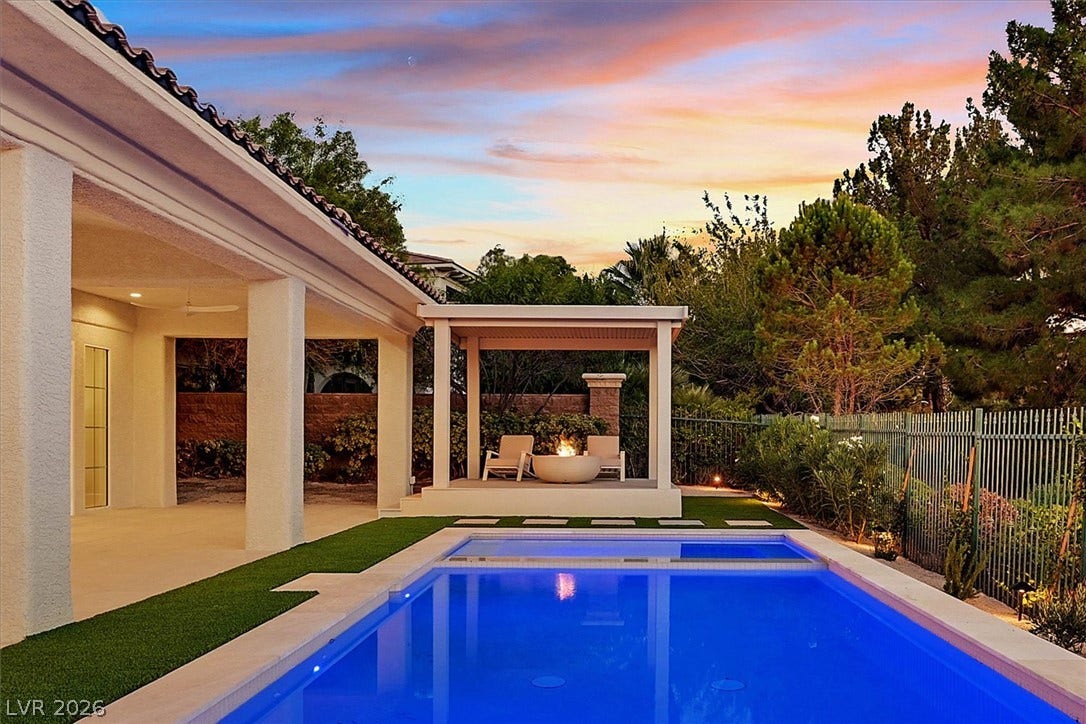 12007 Oakland Hills Drive, Las Vegas, NV 89141 An inviting backyard oasis features a sparkling swimming pool alongside a covered patio area.
