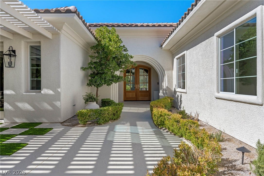 12007 Oakland Hills Drive, Las Vegas, NV 89141 An arched entry and concrete walkway bordered by low hedges lead to double front doors.