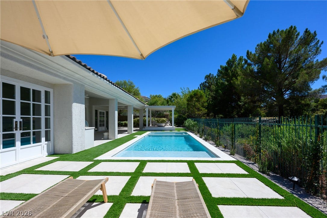 12007 Oakland Hills Drive, Las Vegas, NV 89141 A sparkling swimming pool anchors the backyard alongside modern paver and turf landscaping.