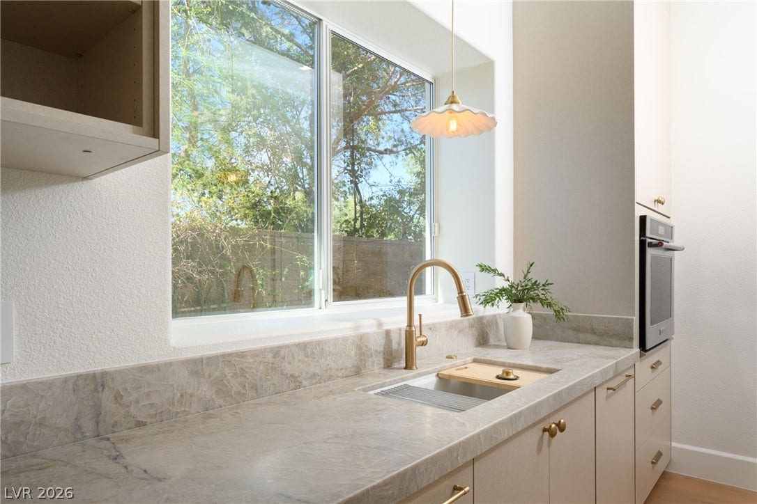 12007 Oakland Hills Drive, Las Vegas, NV 89141 Natural light floods this kitchen workspace featuring stone countertops and a view of the outdoors.