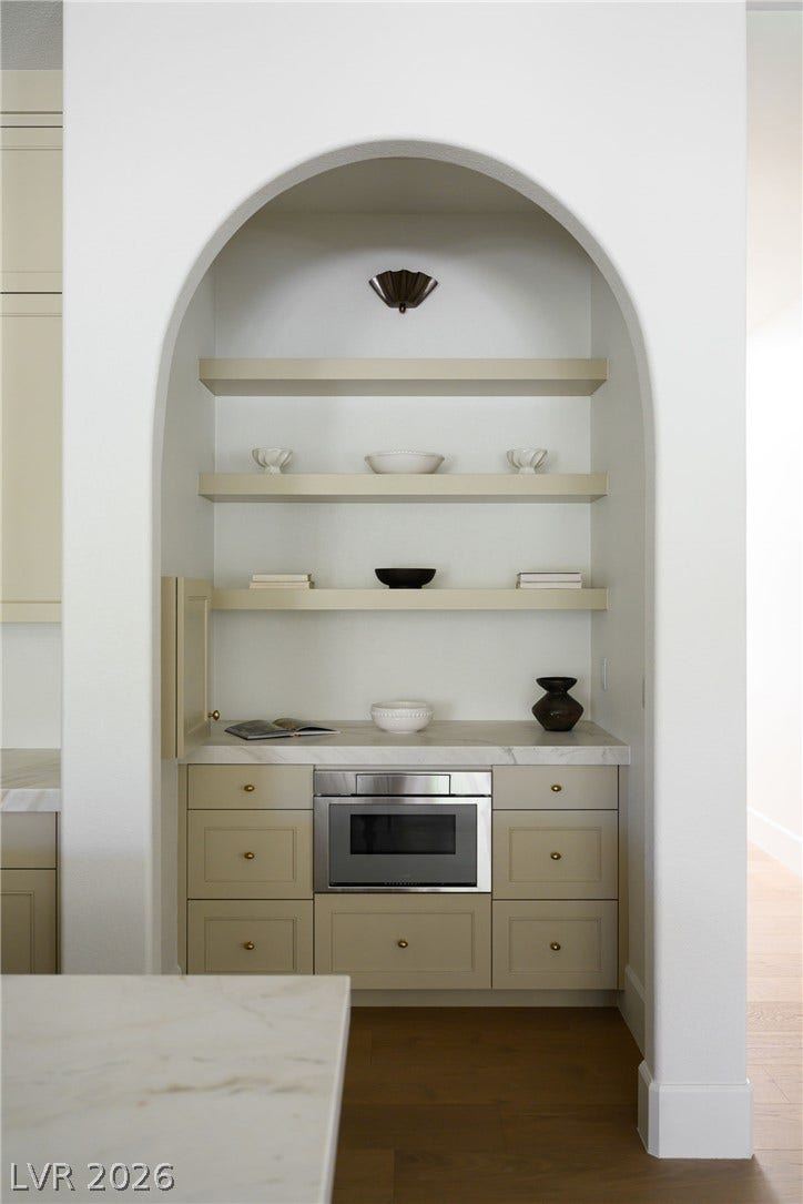 12007 Oakland Hills Drive, Las Vegas, NV 89141 An arched alcove frames built-in shelving, custom cabinetry, and a sleek integrated appliance.