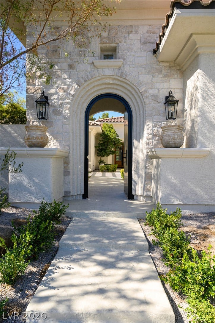 12007 Oakland Hills Drive, Las Vegas, NV 89141 An elegant arched stone entryway guides visitors toward a sunlit private courtyard.