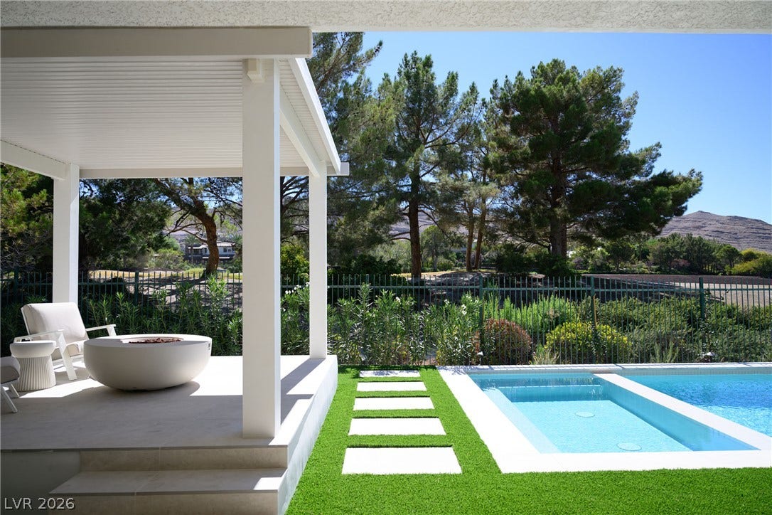 12007 Oakland Hills Drive, Las Vegas, NV 89141 An inviting covered patio steps down to a pristine swimming pool and lush green lawn.