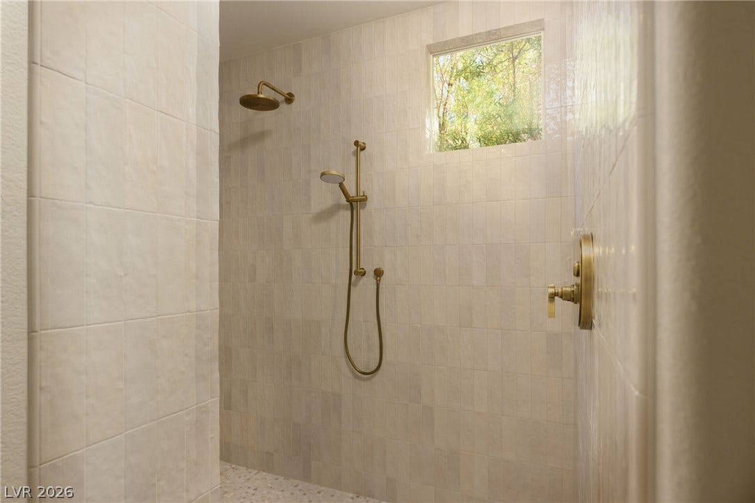 12007 Oakland Hills Drive, Las Vegas, NV 89141 Floor-to-ceiling tiling and a high window create a serene atmosphere in this walk-in shower.