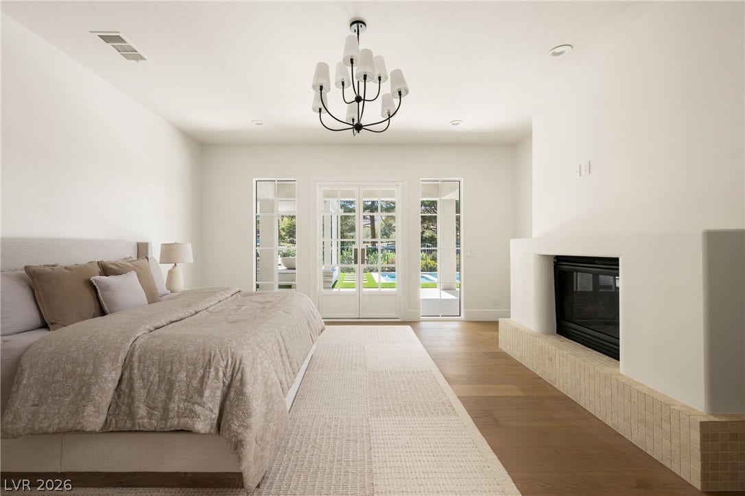 12007 Oakland Hills Drive, Las Vegas, NV 89141 A modern fireplace on a tiled hearth anchors this serene bedroom with wood floors.