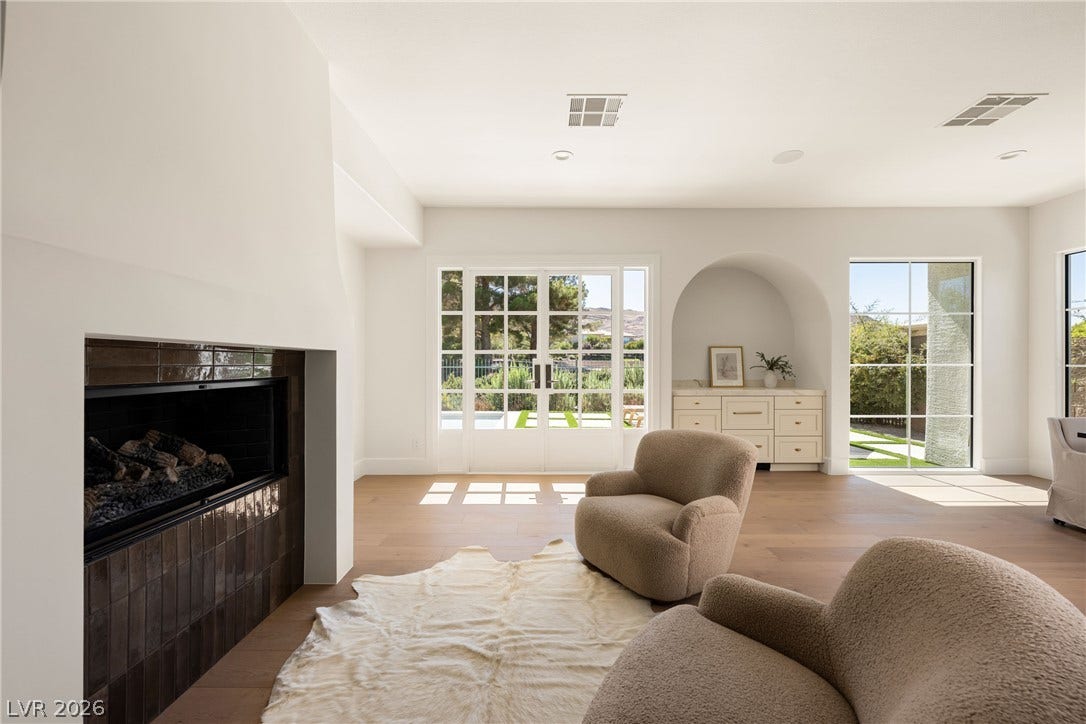 12007 Oakland Hills Drive, Las Vegas, NV 89141 A sleek fireplace anchors this airy living space finished with warm wood flooring.