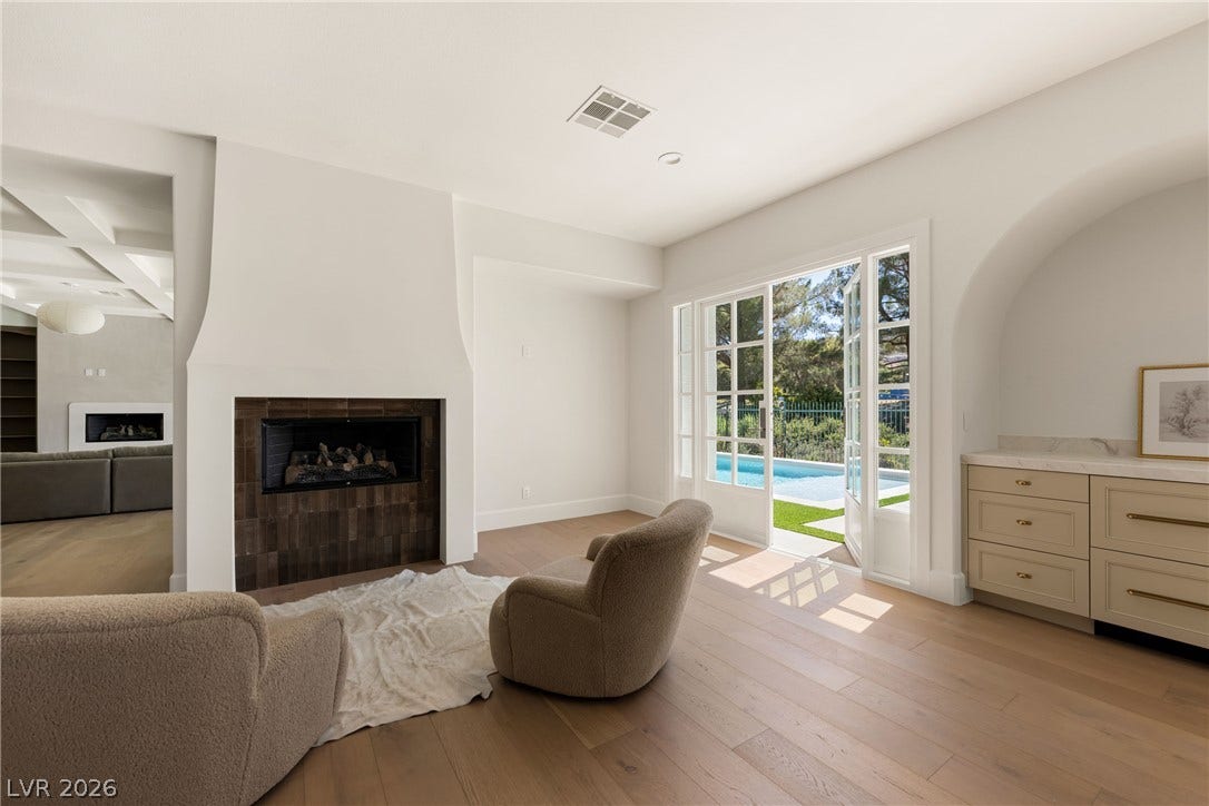 12007 Oakland Hills Drive, Las Vegas, NV 89141 A modern fireplace and wide wood plank flooring anchor this light-filled room opening to the pool.