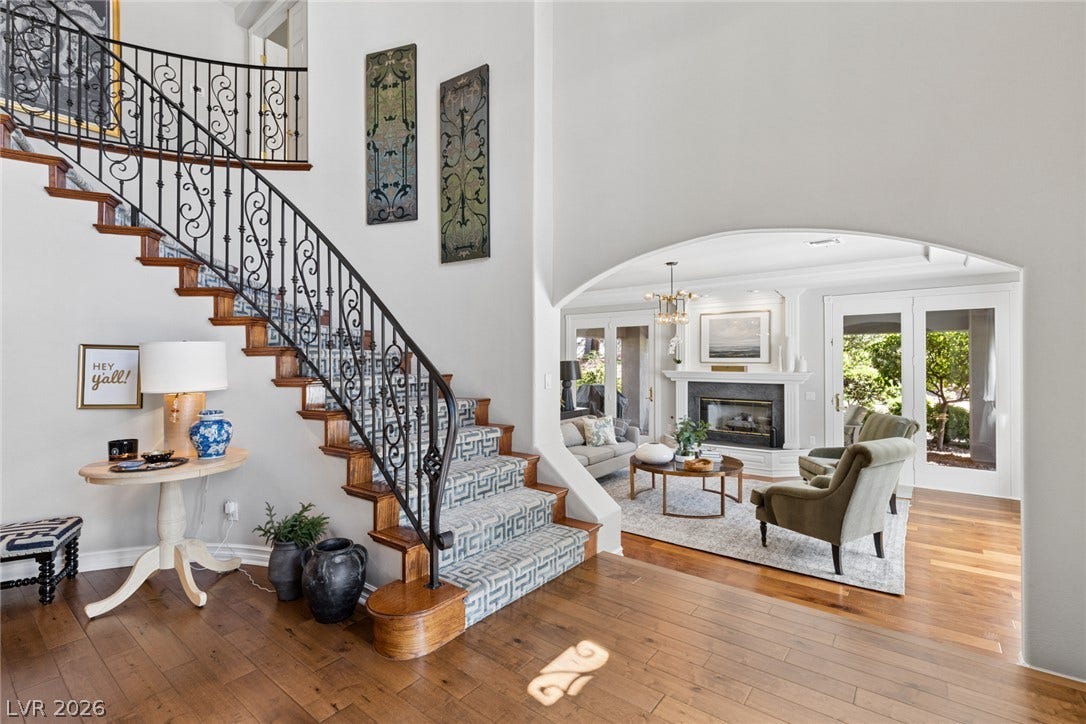 9916 Aspen Knoll Court, Las Vegas, NV 89117 An elegant staircase with wrought-iron railings rises beside an arched opening to the living room. Note French doors to side yard patio.
