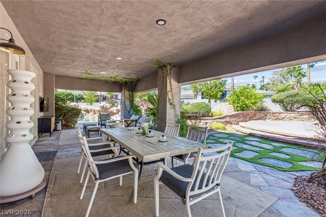 9916 Aspen Knoll Court, Las Vegas, NV 89117 A spacious covered patio features textured concrete ceilings and stone tile flooring overlooking the yard. right off the kitchen dinning area. Back right is a open patio for more entertaining. Synthetic grass shown throughout yard.