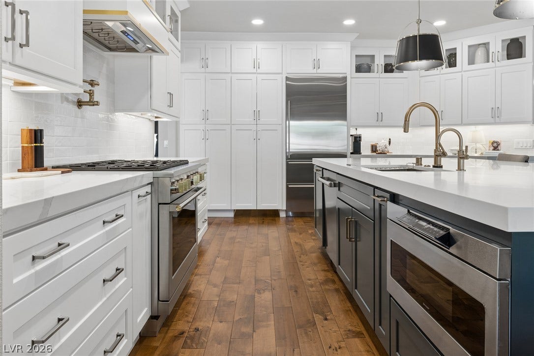 9916 Aspen Knoll Court, Las Vegas, NV 89117 Five burner Monogram cooktop & oven with microwave at front and dishwasher visible at rear of island. Note pot filler & well designed vent hood.