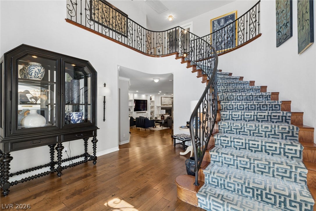 9916 Aspen Knoll Court, Las Vegas, NV 89117 A curved staircase with intricate wrought-iron railings rises from the entry hall's rich hardwood floors. From entry looking towards family room.