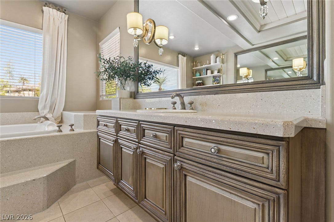 9916 Aspen Knoll Court, Las Vegas, NV 89117 An elegant vanity and a deep soaking tub highlight this beautifully appointed primary bathroom.