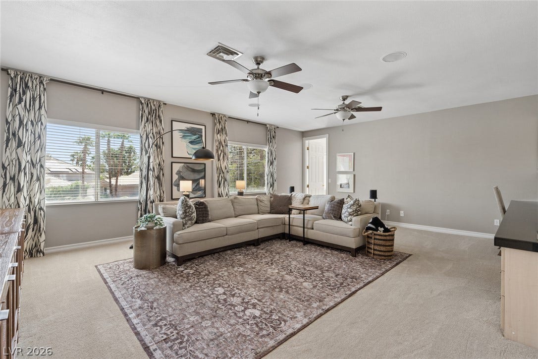 9916 Aspen Knoll Court, Las Vegas, NV 89117 An open living space features soft neutral walls, classic carpeting, and large windows. Door at rear right is half bath.