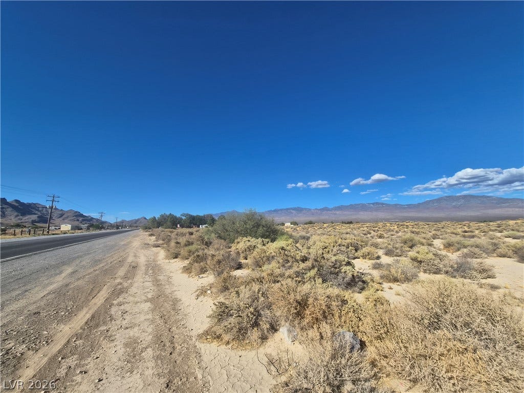 4221 N Leslie Street, Pahrump, NV 89060 Vast desert acreage sits alongside a paved road under a clear blue sky.