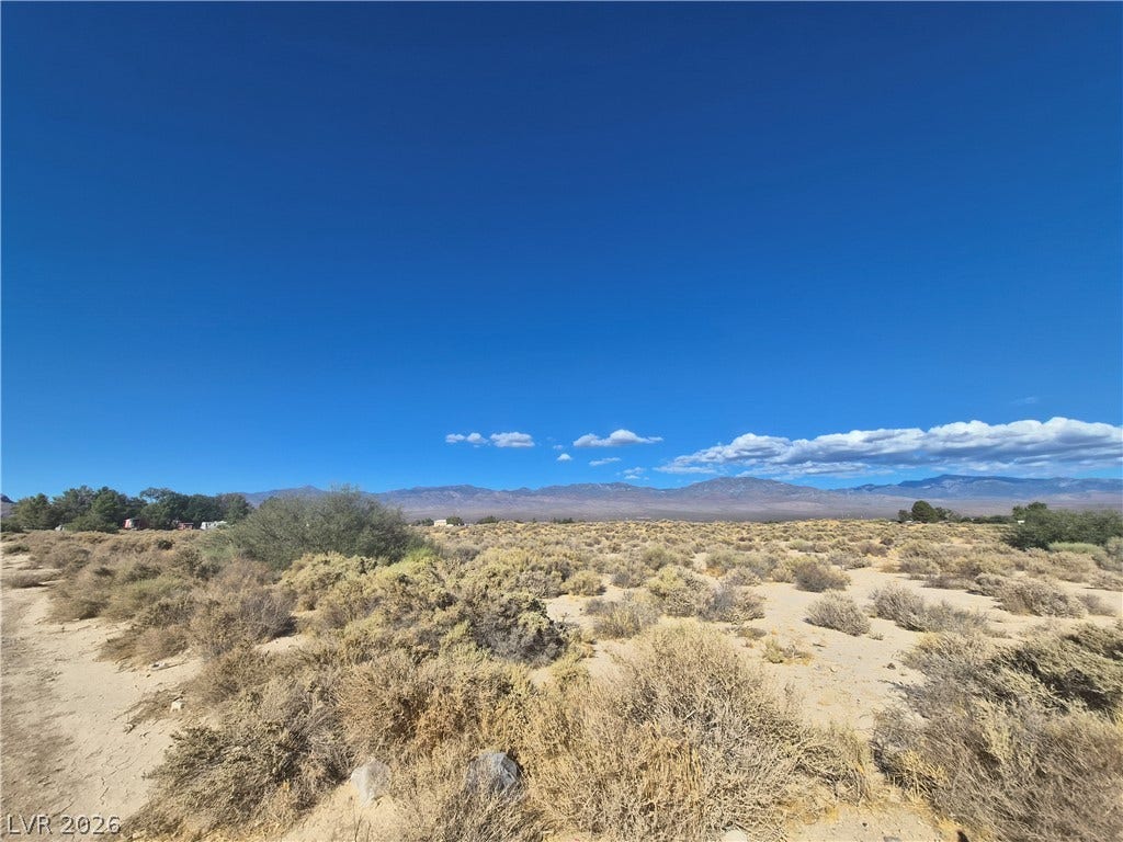 4221 N Leslie Street, Pahrump, NV 89060 Distant mountains frame this open desert acreage under a clear blue sky.