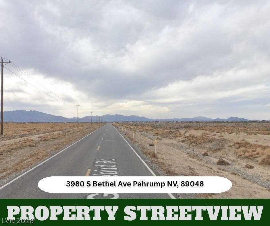 A long paved road leads through the desert toward distant mountain ridges under cloudy skies.