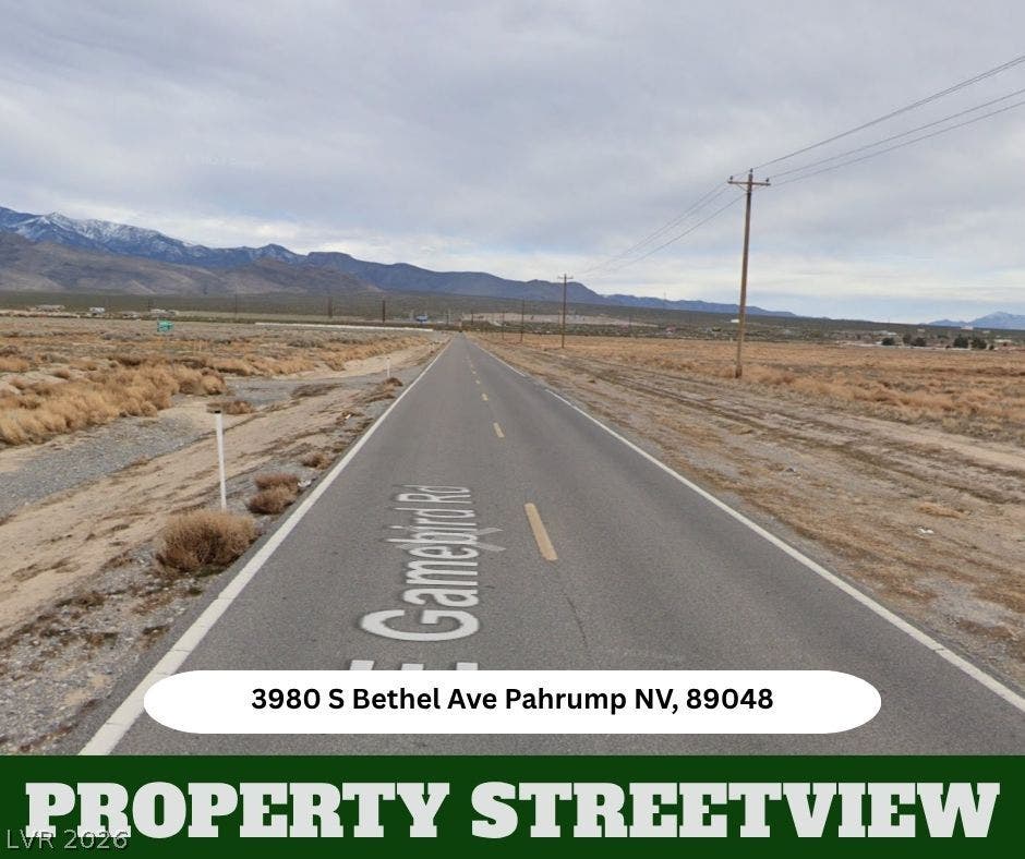 Dramatic mountain ranges frame the wide desert horizon along this paved roadway access.