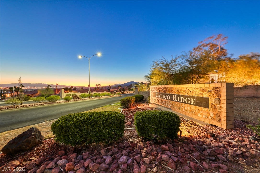 1157 Big Bird Court, Henderson, NV 89011 A stone monument sign marks the entrance to this desert hillside community under twilight skies.