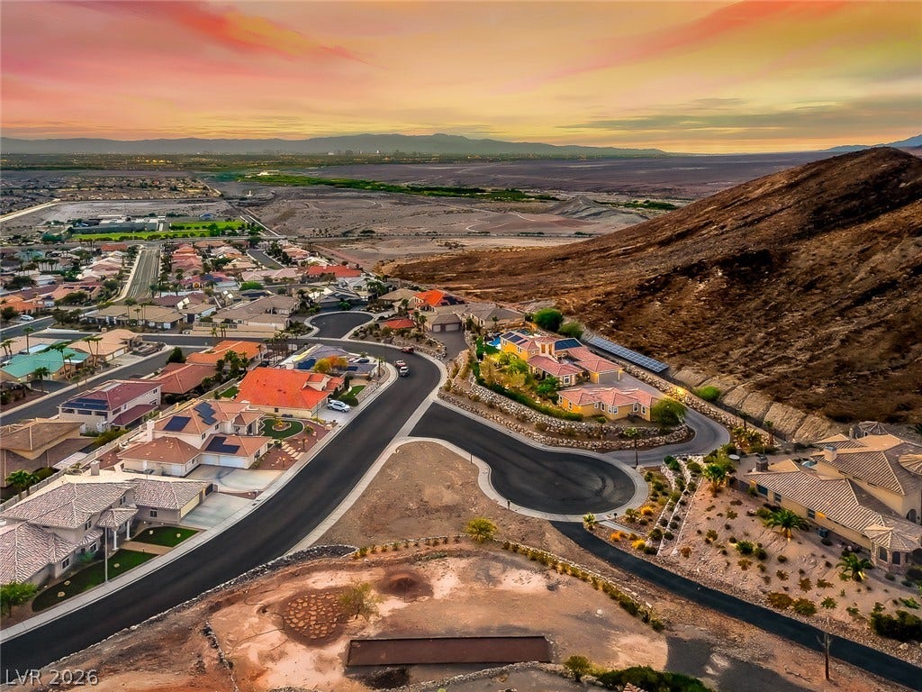 1157 Big Bird Court, Henderson, NV 89011 Dramatic mountain vistas frame this peaceful hillside neighborhood nestled beneath vibrant sunset skies.