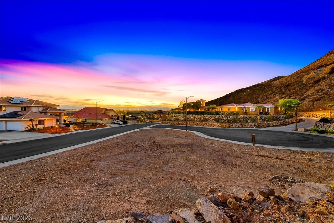 1157 Big Bird Court, Henderson, NV 89011 A spacious hillside lot overlooks the surrounding neighborhood and distant city lights at sunset.