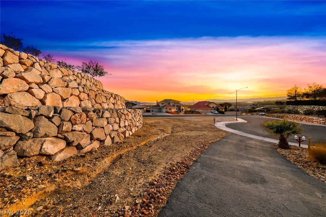 1157 Big Bird Court, Henderson, NV 89011 A paved path winds past stone retaining walls toward sweeping neighborhood and sunset views.