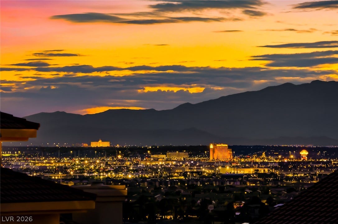 1157 Big Bird Court, Henderson, NV 89011 Glimmering city lights stretch across the valley below towering mountain silhouettes.