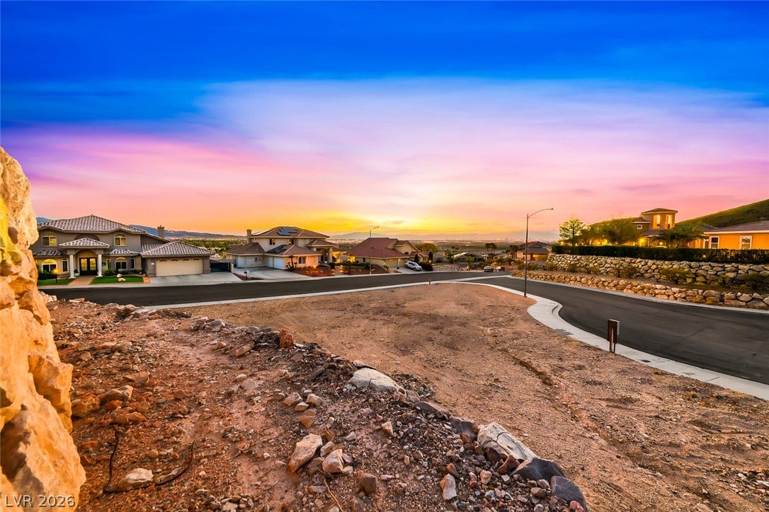 1157 Big Bird Court, Henderson, NV 89011 A spacious residential lot overlooks the surrounding neighborhood under a vibrant sunset sky.