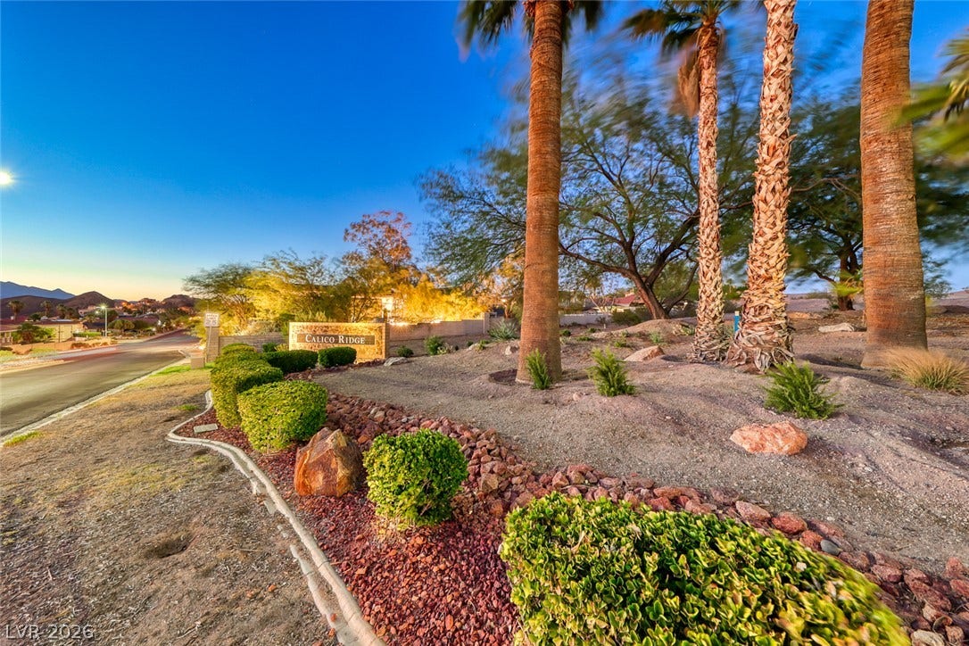 1157 Big Bird Court, Henderson, NV 89011 Lush desert landscaping welcomes residents at the entrance of Calico Ridge under dusk skies.