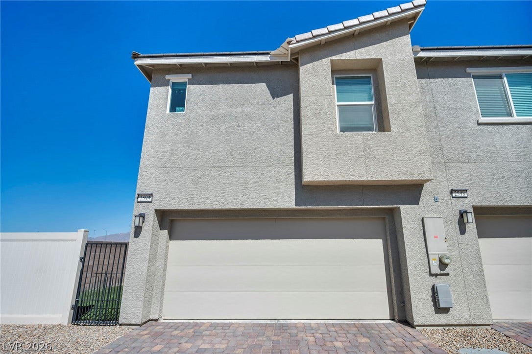 2594 Canary Yellow Court, North Las Vegas, NV 89086 Modern stucco exterior features a spacious garage with a paver driveway under clear skies.
