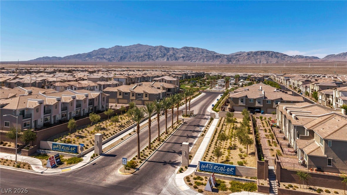 2594 Canary Yellow Court, North Las Vegas, NV 89086 A gated entrance with palm trees frames mountain views beyond the residential neighborhood.