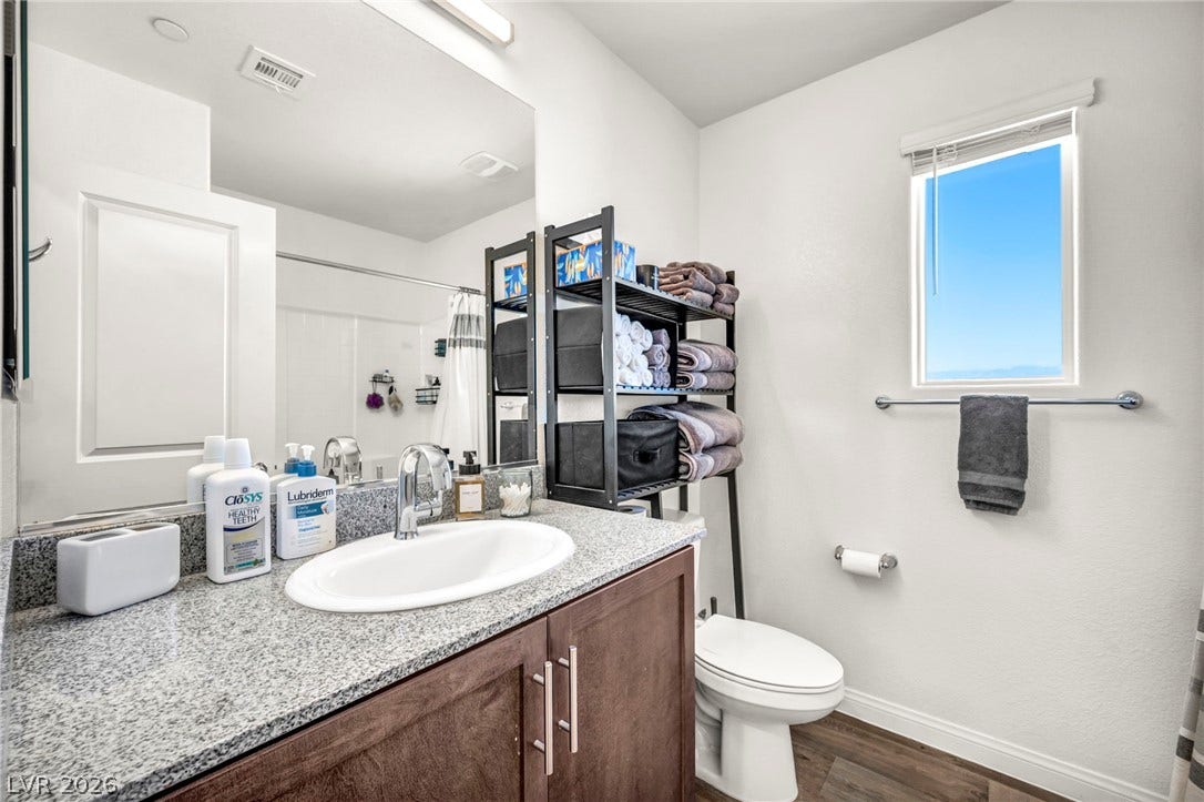 2594 Canary Yellow Court, North Las Vegas, NV 89086 Polished granite countertops and wood-look flooring define this bright, functional bathroom space.