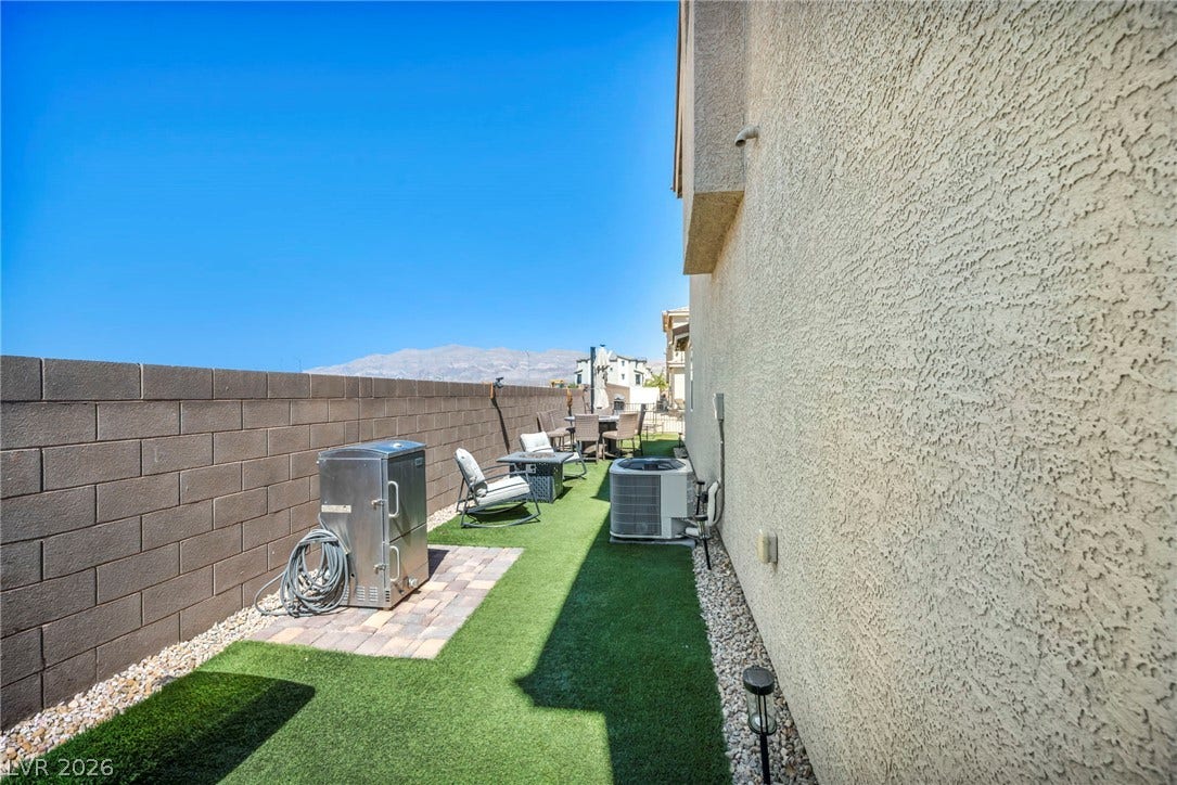 2594 Canary Yellow Court, North Las Vegas, NV 89086 An inviting side yard features synthetic turf alongside a textured stucco exterior wall.