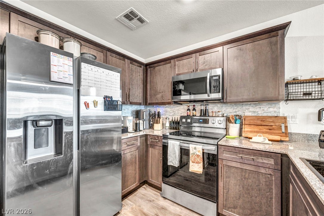 2594 Canary Yellow Court, North Las Vegas, NV 89086 Rich wood cabinetry paired with stone countertops defines this functional kitchen space.