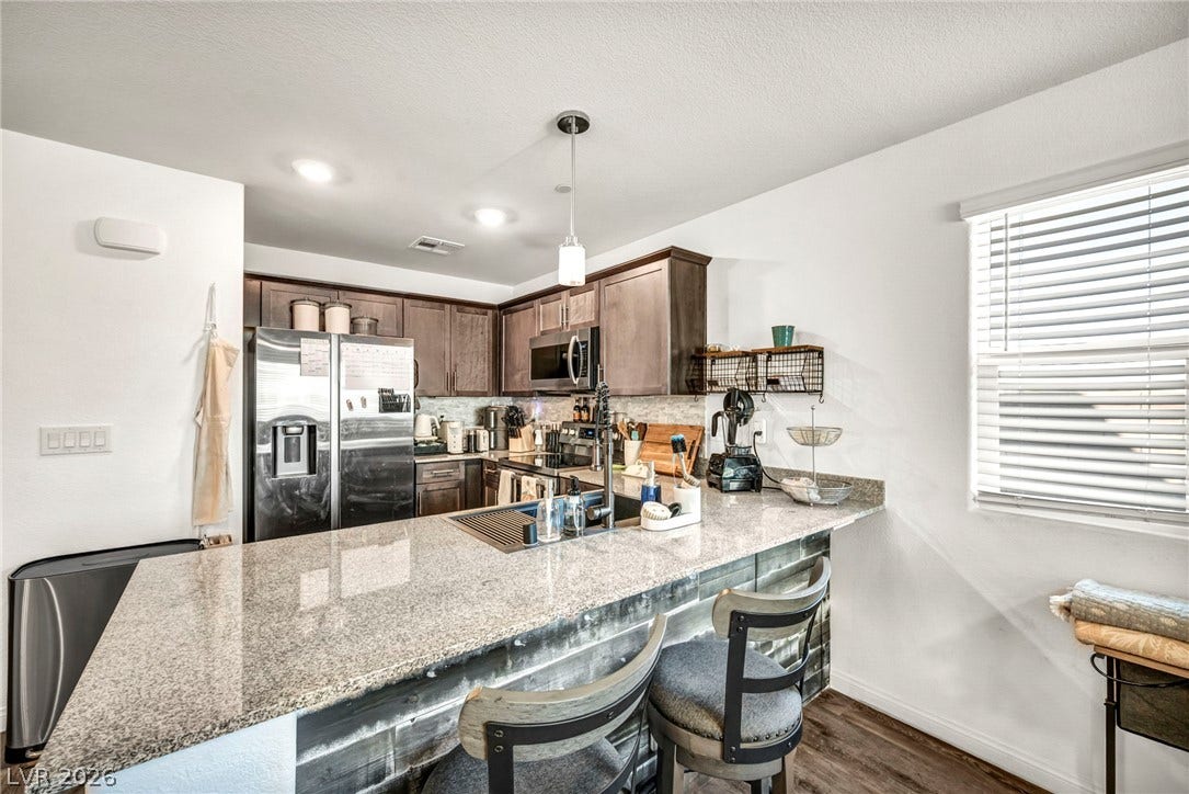 2594 Canary Yellow Court, North Las Vegas, NV 89086 Granite countertops and rich wooden cabinetry anchor this functional cooking space.