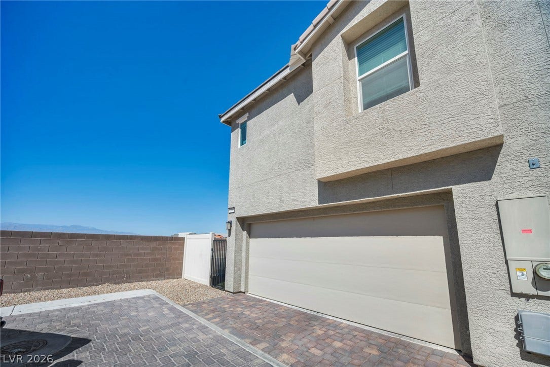 2594 Canary Yellow Court, North Las Vegas, NV 89086 A spacious garage fronted by a classic brick driveway stands ready beneath a clear blue sky.