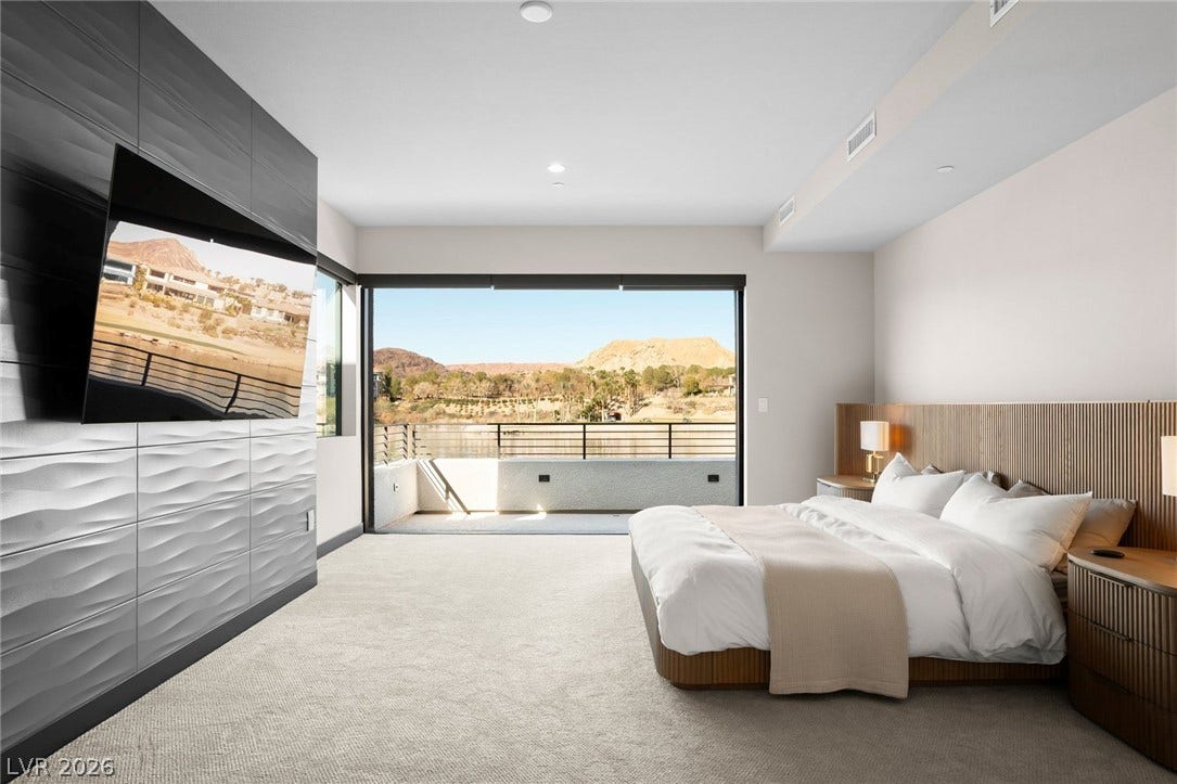34 Lakefront Drive, Henderson, NV 89011 Sliding doors frame breathtaking desert mountain views from this modern primary bedroom suite.