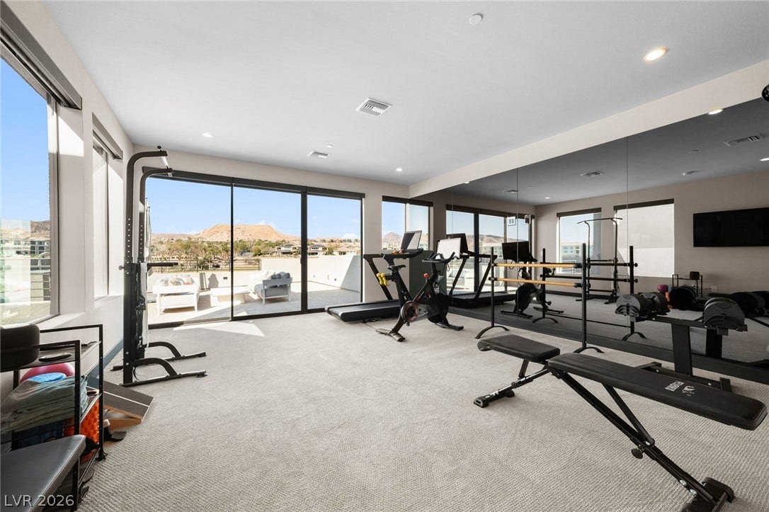 34 Lakefront Drive, Henderson, NV 89011 A spacious home gym showcases soft carpeting, mirrored walls, and glass doors opening to scenic views.