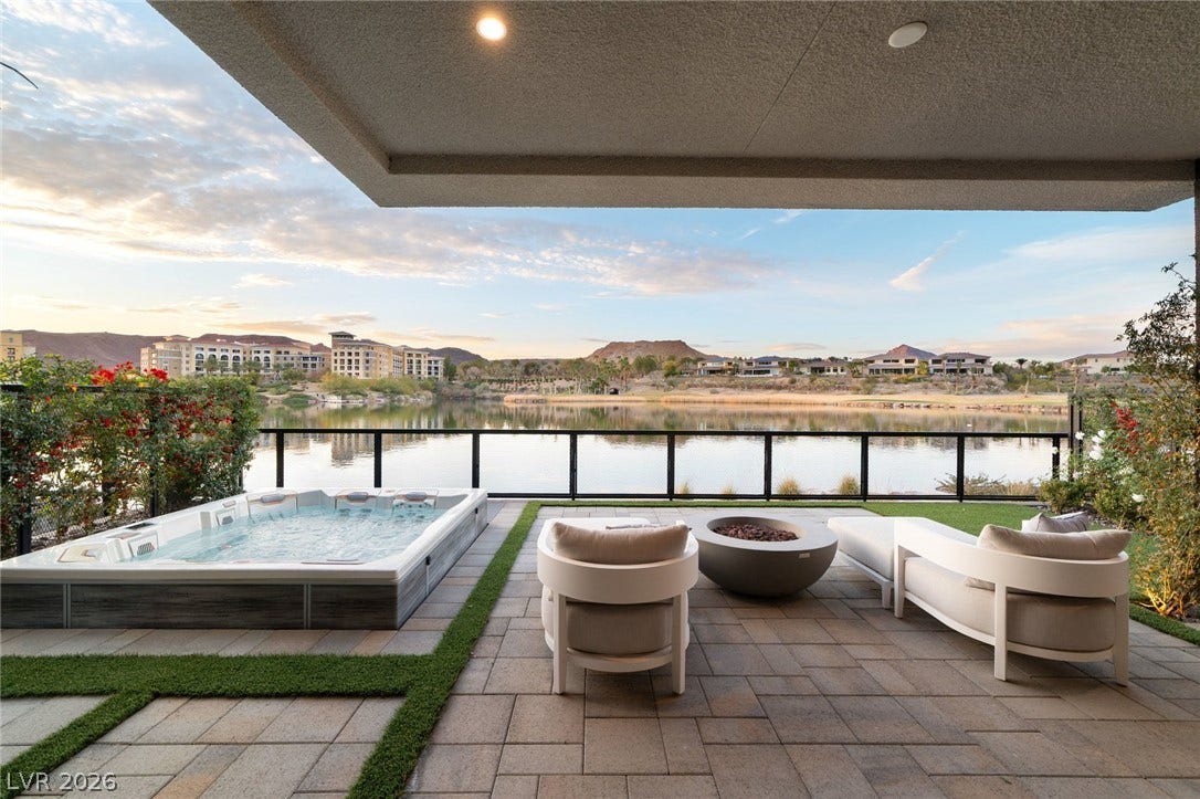 34 Lakefront Drive, Henderson, NV 89011 A spacious stone patio overlooks serene waters and distant mountain peaks under open skies.