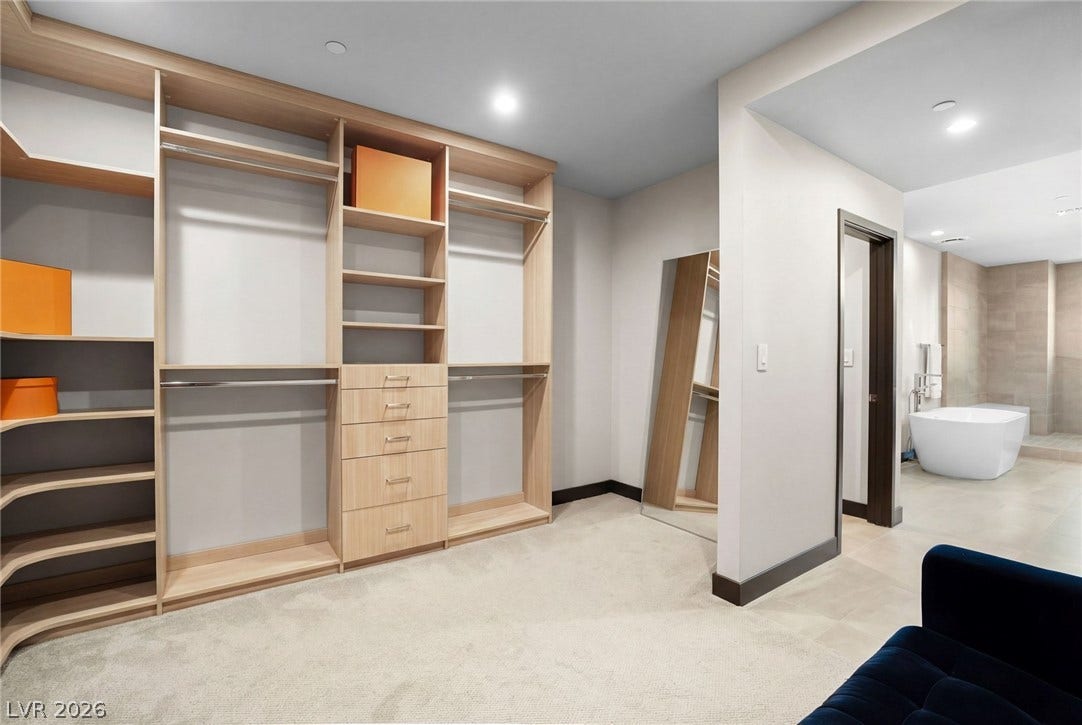 34 Lakefront Drive, Henderson, NV 89011 Custom built-in shelving and soft carpeting define this spacious dressing area with adjoining bath access.