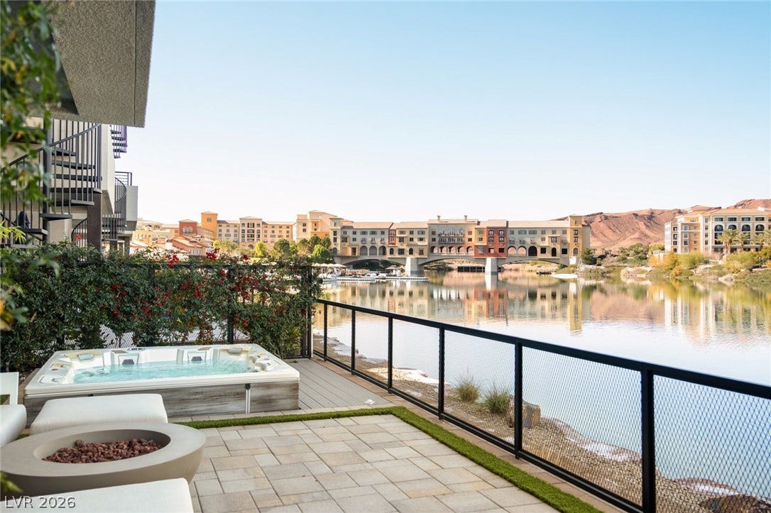 34 Lakefront Drive, Henderson, NV 89011 A spacious stone patio overlooks serene waters with distant mountain and architectural backdrops.