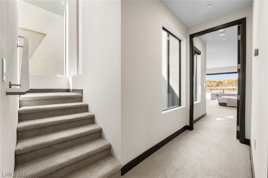 34 Lakefront Drive, Henderson, NV 89011 Crisp white walls and clean architectural lines define this carpeted hallway and staircase.
