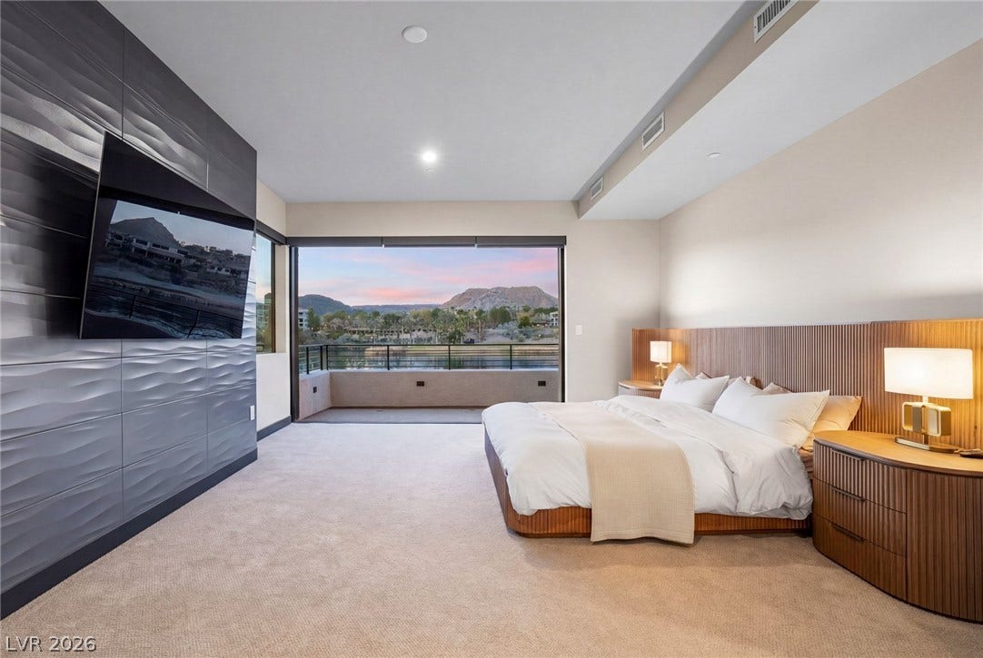 34 Lakefront Drive, Henderson, NV 89011 Gliding glass doors connect this primary bedroom to a private balcony framing mountain views.